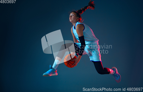 Image of Young caucasian female basketball player on blue studio background in neon light