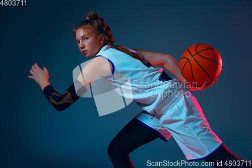 Image of Young caucasian female basketball player on blue studio background in neon light