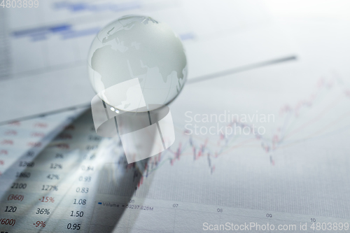 Image of Glass of globe over stock market chart