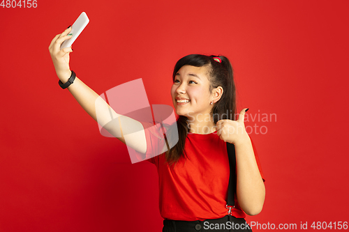 Image of Asian teenager\'s portrait isolated on red studio background