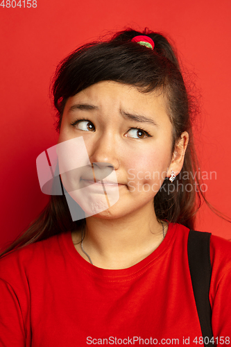 Image of Asian teenager\'s close up portrait isolated on red studio background