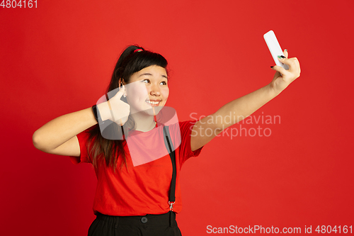 Image of Asian teenager\'s portrait isolated on red studio background