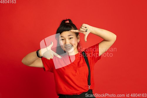 Image of Asian teenager\'s portrait isolated on red studio background