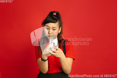 Image of Asian teenager\'s portrait isolated on red studio background