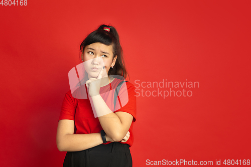 Image of Asian teenager\'s portrait isolated on red studio background