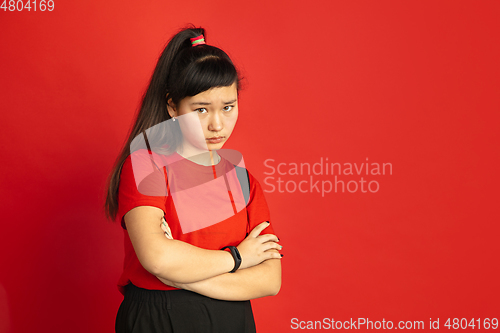 Image of Asian teenager\'s portrait isolated on red studio background