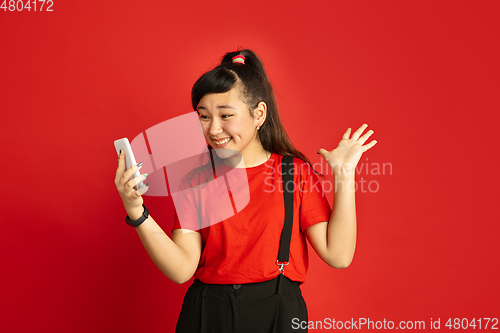 Image of Asian teenager\'s portrait isolated on red studio background