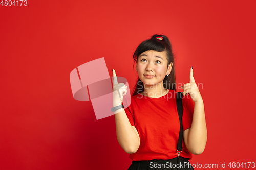 Image of Asian teenager\'s portrait isolated on red studio background