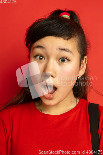 Image of Asian teenager\'s close up portrait isolated on red studio background