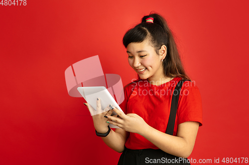 Image of Asian teenager\'s portrait isolated on red studio background
