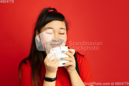 Image of Asian teenager\'s portrait isolated on red studio background