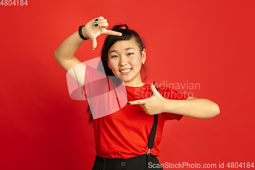 Image of Asian teenager\'s portrait isolated on red studio background