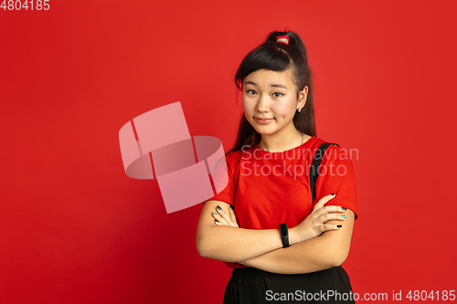 Image of Asian teenager\'s portrait isolated on red studio background