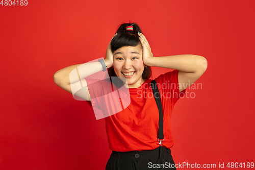 Image of Asian teenager\'s portrait isolated on red studio background