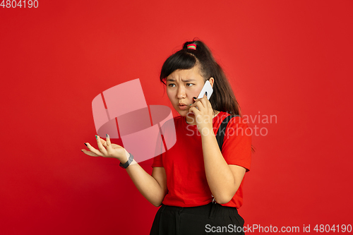Image of Asian teenager\'s portrait isolated on red studio background