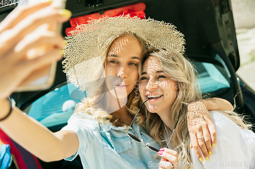 Image of Young lesbian\'s couple preparing for vacation trip on the car in sunny day