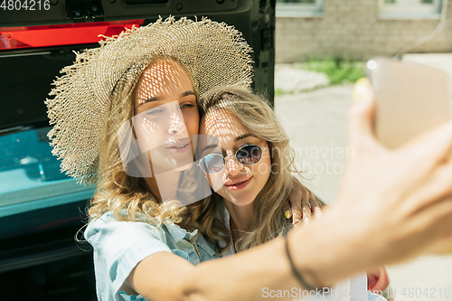 Image of Young lesbian\'s couple preparing for vacation trip on the car in sunny day