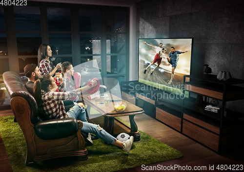 Image of Group of friends watching TV, football match, sport together