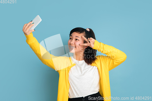 Image of Asian teenager\'s portrait isolated on blue studio background