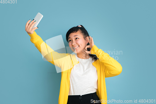 Image of Asian teenager\'s portrait isolated on blue studio background