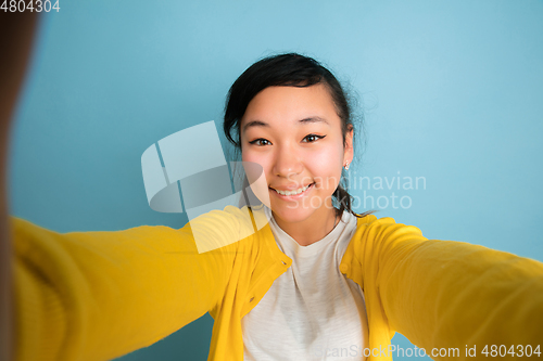 Image of Asian teenager\'s portrait isolated on blue studio background