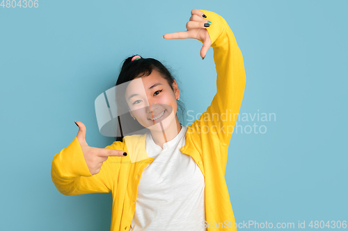 Image of Asian teenager\'s portrait isolated on blue studio background
