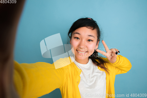 Image of Asian teenager\'s portrait isolated on blue studio background