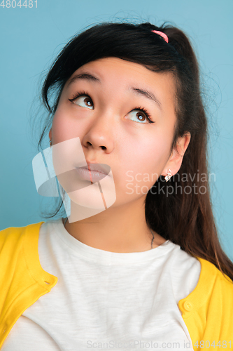 Image of Asian teenager\'s close up portrait isolated on blue studio background