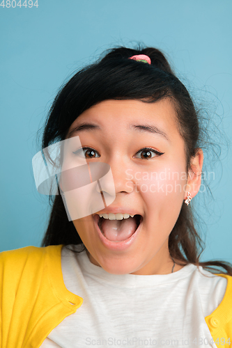 Image of Asian teenager\'s close up portrait isolated on blue studio background