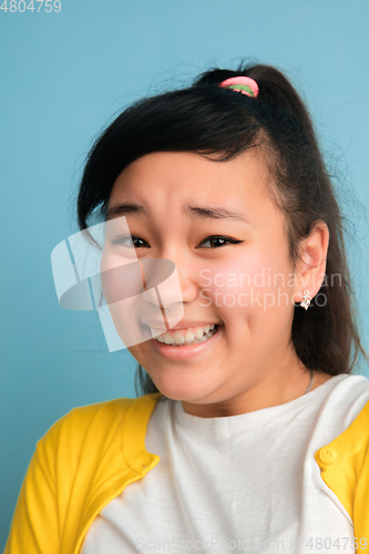 Image of Asian teenager\'s close up portrait isolated on blue studio background