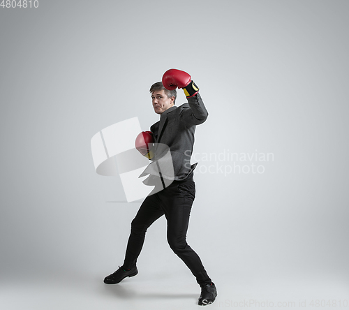 Image of Caucasian man in office clothes boxing isolated on grey studio background