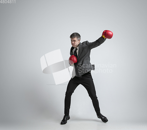 Image of Caucasian man in office clothes boxing isolated on grey studio background