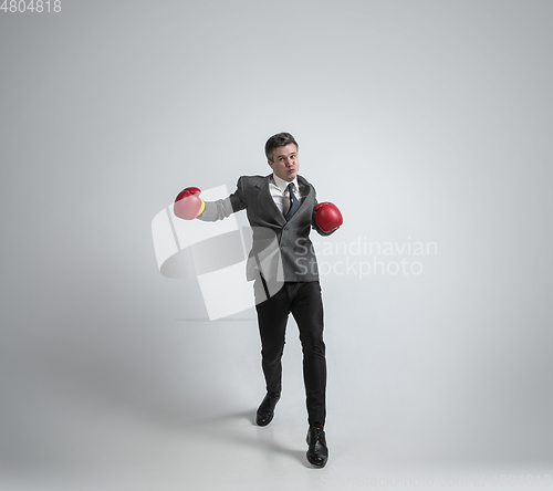Image of Caucasian man in office clothes boxing isolated on grey studio background