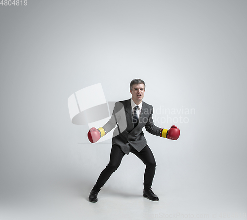 Image of Caucasian man in office clothes boxing isolated on grey studio background