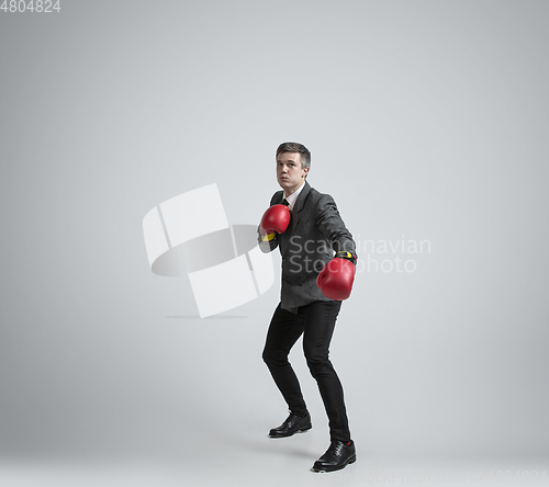 Image of Caucasian man in office clothes boxing isolated on grey studio background