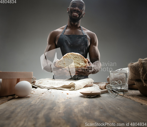 Image of Close up of african-american man cooks bread at craft kitchen