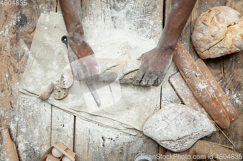 Image of Top view of african-american man cooks bread at craft kitchen