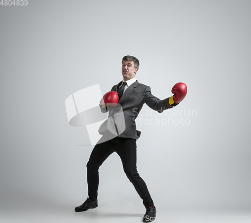 Image of Caucasian man in office clothes boxing isolated on grey studio background