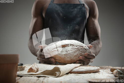 Image of Close up of african-american man cooks bread at craft kitchen