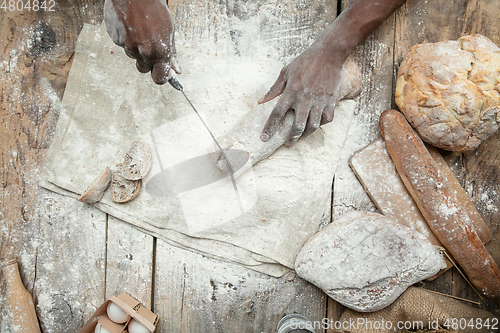 Image of Top view of african-american man cooks bread at craft kitchen