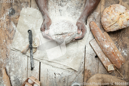 Image of Top view of african-american man cooks bread at craft kitchen
