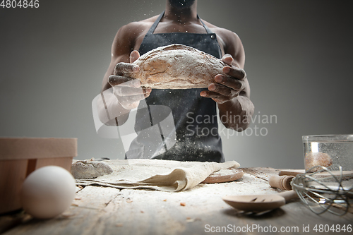 Image of Close up of african-american man cooks bread at craft kitchen