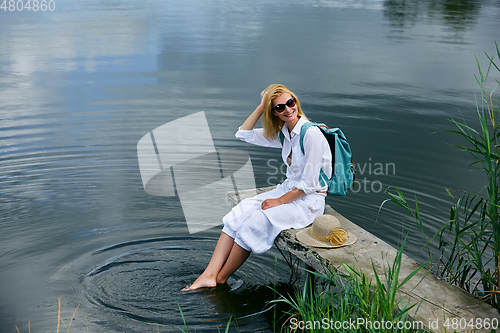 Image of Young woman resting near lake