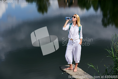 Image of Young woman resting near lake