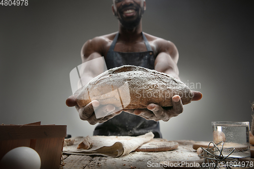 Image of Close up of african-american man cooks bread at craft kitchen