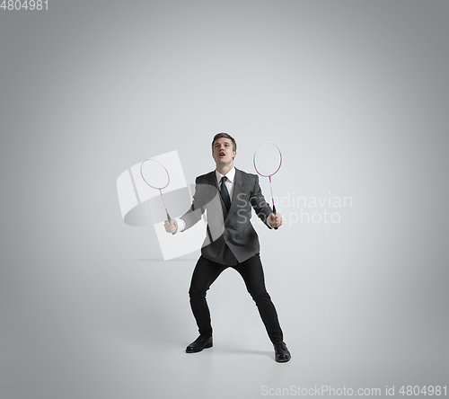 Image of Caucasian man in office clothes plays badminton isolated on grey studio background