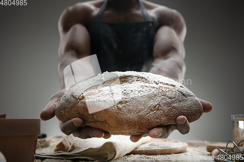 Image of Close up of african-american man cooks bread at craft kitchen