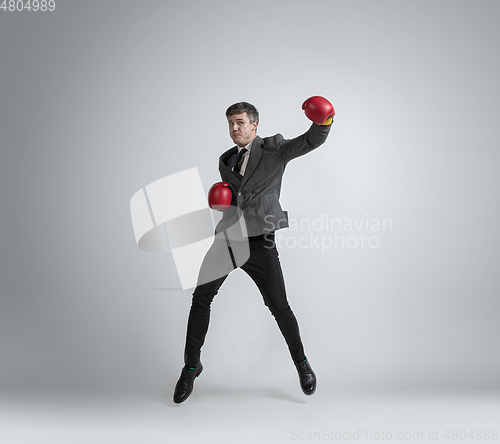 Image of Caucasian man in office clothes boxing isolated on grey studio background