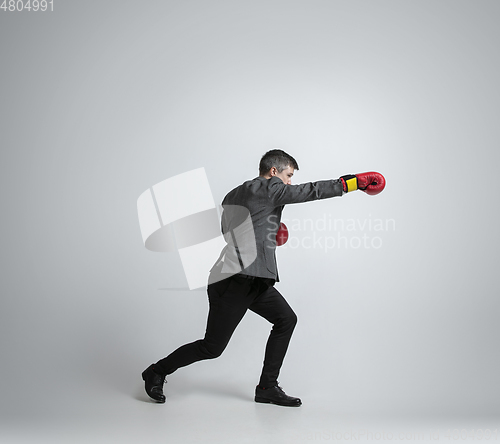 Image of Caucasian man in office clothes boxing isolated on grey studio background