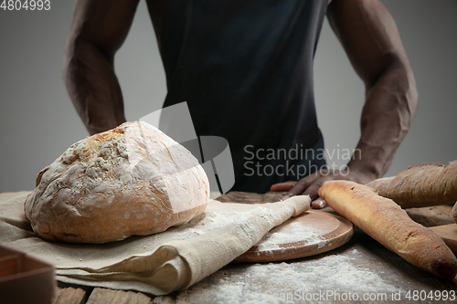 Image of Close up of african-american man cooks bread at craft kitchen